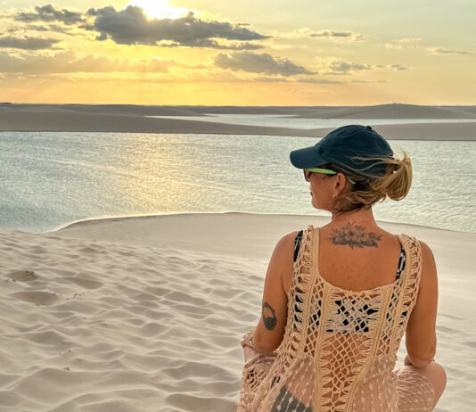 7 erros ao viajar sozinha pela primeira vez (e como evitar cada um) mulher em viagem solo feminina contemplando dunas ao pôr do sol refletindo sobre erros na primeira viagem sozinha